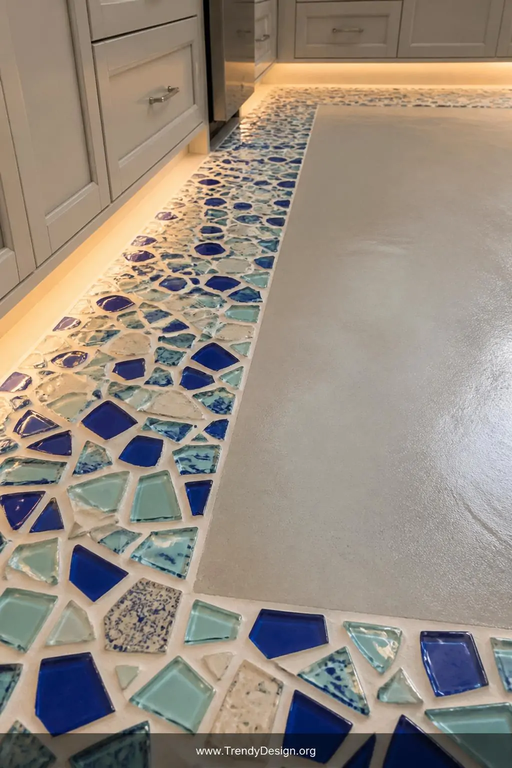 Closeup photorealistic shot of a handcrafted mosaic accent border running along a kitchen floor perimeter, composed of broken