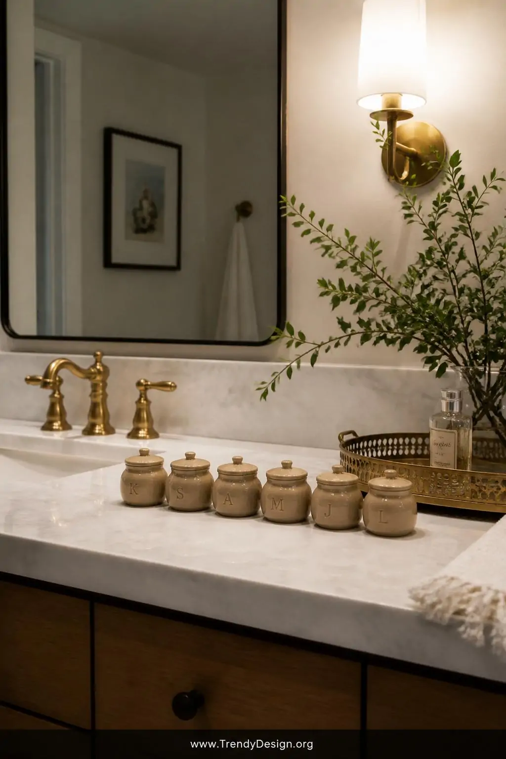 Set of six tiny two-inch clay coil pots with stamped initial details and miniature pinched lids lined up on a marble bathroom vanity beside a gold tray, soft warm vanity light, wide shot